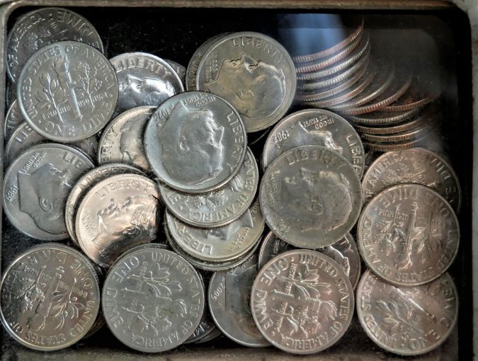 Caja con muchas monedas de 10 centavos de dólar.