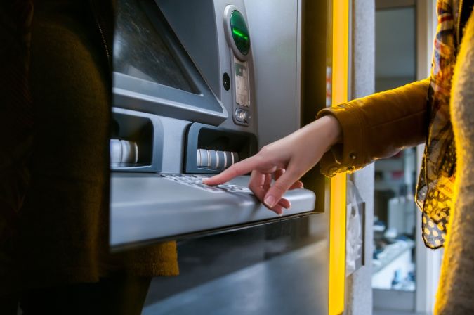 Señora usando cajero automático para retirar su dinero.