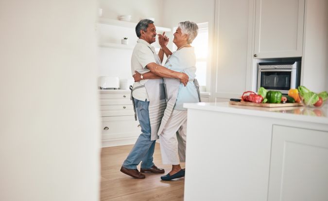 Una pareja feliz de edad avanzada baila juntos en la cocina.