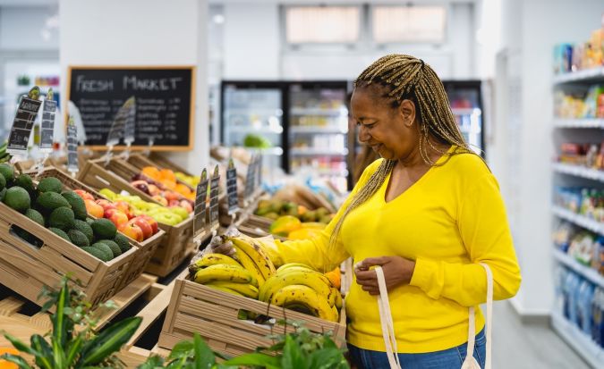 Mujer africana mayor comprando frutas frescas en el supermercado.