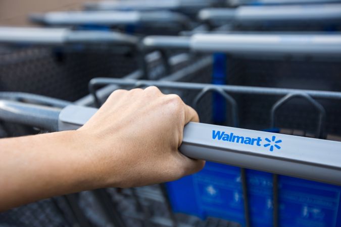 Mujer con carrito de compras cerca del supermercado Walmart.