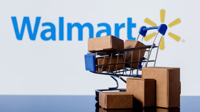 Carrito de compras con paquetes sobre el fondo del logotipo de Walmart.