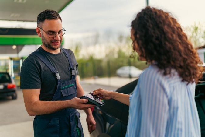 Una joven paga combustible en una gasolinera con una tarjeta, el trabajador le entregó una terminal para pagar.