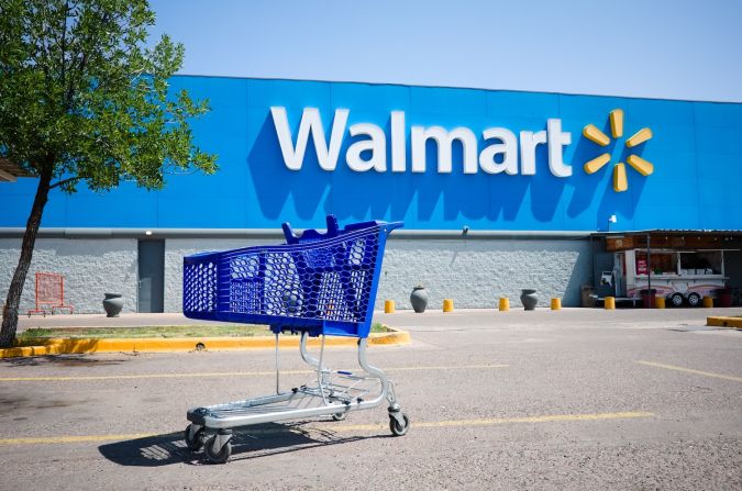 Carrito de compras en un estacionamiento frente a la entrada principal del supermercado Walmart.