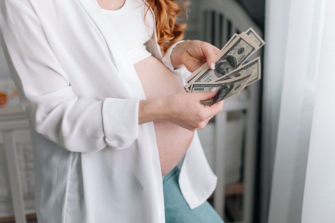 Mujer embarazada contando dólares.