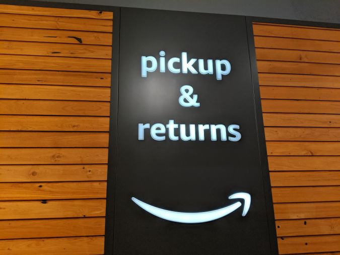 Recogida y devolución de libros en tienda de Amazon. Cartel de sonrisa por la noche.